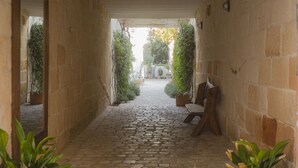 A stone-paved corridor with a wooden bench and potted plants. - Coliving AdD LiVitum (Ciutadella de Menorca)