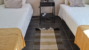 A bedroom with two beds, a small table with a lamp, and a rug. - Sleep & Go Faro Airport Guest House (Faro)