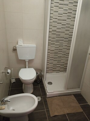 Bathroom features a toilet, sink, and glass-enclosed shower with a geometric-patterned wall.