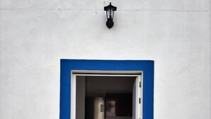 A doorway leading to a kitchen with cabinets and a refrigerator. - Sleep & Go Faro Airport Guest House (Faro)