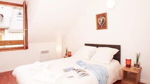 A bedroom with a bed, a window, a bedside table, and a wall-mounted picture. - Wifi, Ground floor, swimming pool, terrace, tv, 50m², Saint Lary Soulan (Vignec)