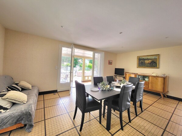 A dining area with a table set for four, a sofa, and a television on a stand.