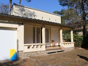 A two-story building with a covered porch and a stone foundation.