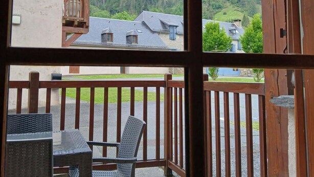 A wooden balcony with a table and chairs, overlooking a mountainous landscape with houses. - Wifi, Ground floor, swimming pool, terrace, tv, 37m², Saint Lary Soulan (Vignec)
