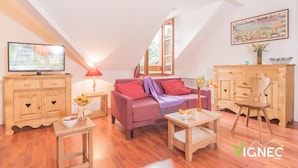 A cozy room with a wooden cabinet, a sofa, a small table, and a television. - Wifi, Ground floor, swimming pool, terrace, tv, 37m², Saint Lary Soulan (Vignec)