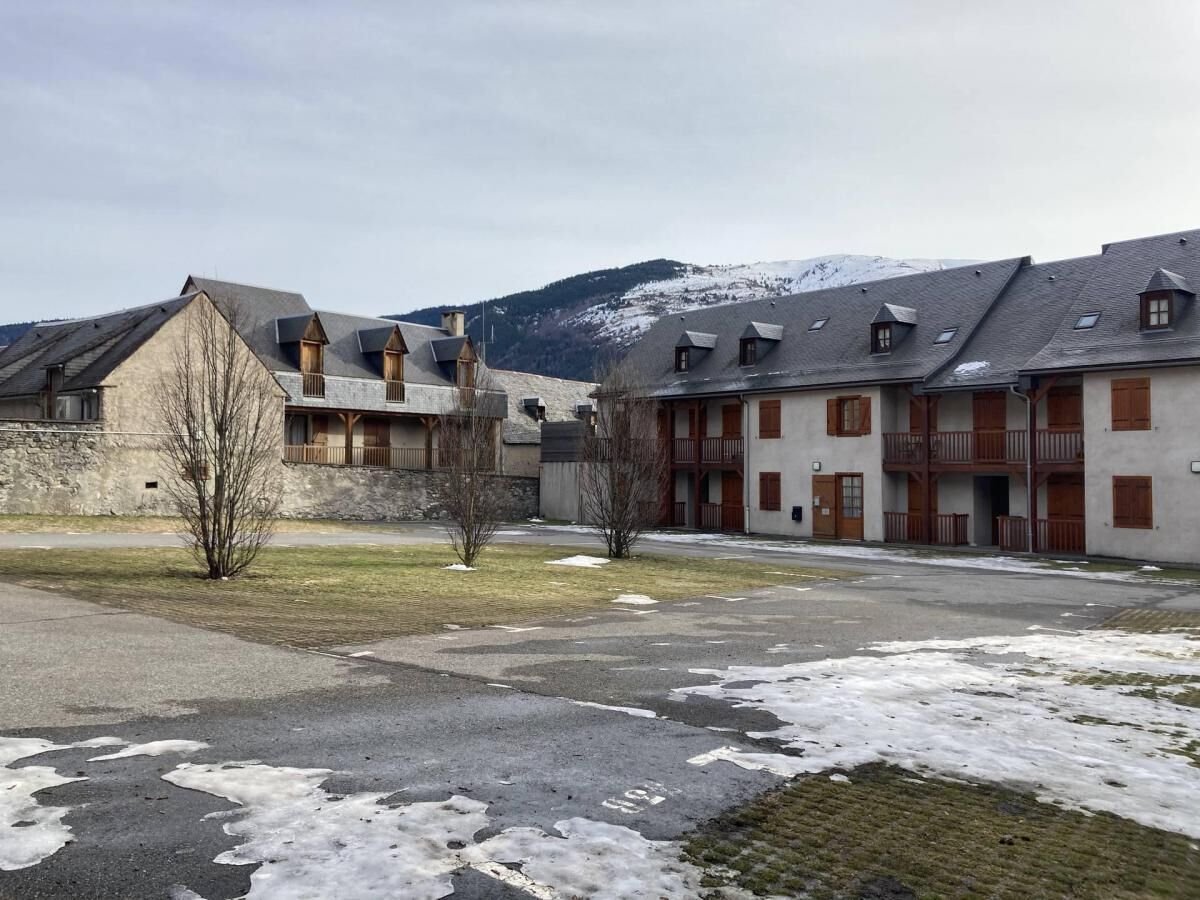 A building complex with multiple balconies and a mountainous backdrop.