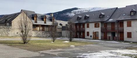 A building complex with multiple balconies and a mountainous backdrop.