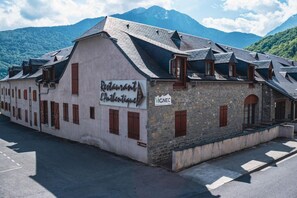 Een gebouw met een bordje voor 'Restaurant L'Authentique' en een 'VIGNEC' bord, omgeven door bergen.