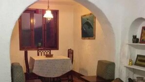 Una sala de estar acogedora con comedor, que presenta un arco de entrada, una mesa de comedor con sillas, un sofá y una pequeña mesa con adornos.