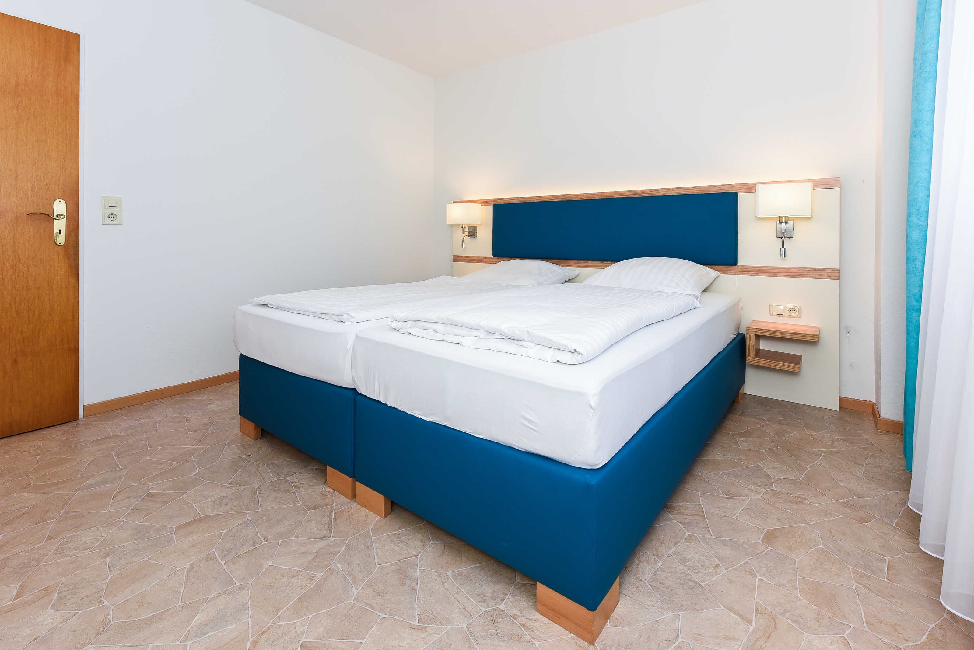 A bedroom with a bed, bedside tables, and a door.