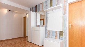 Una habitación con suelo de baldosas, muebles de cocina blancos y una puerta de madera.