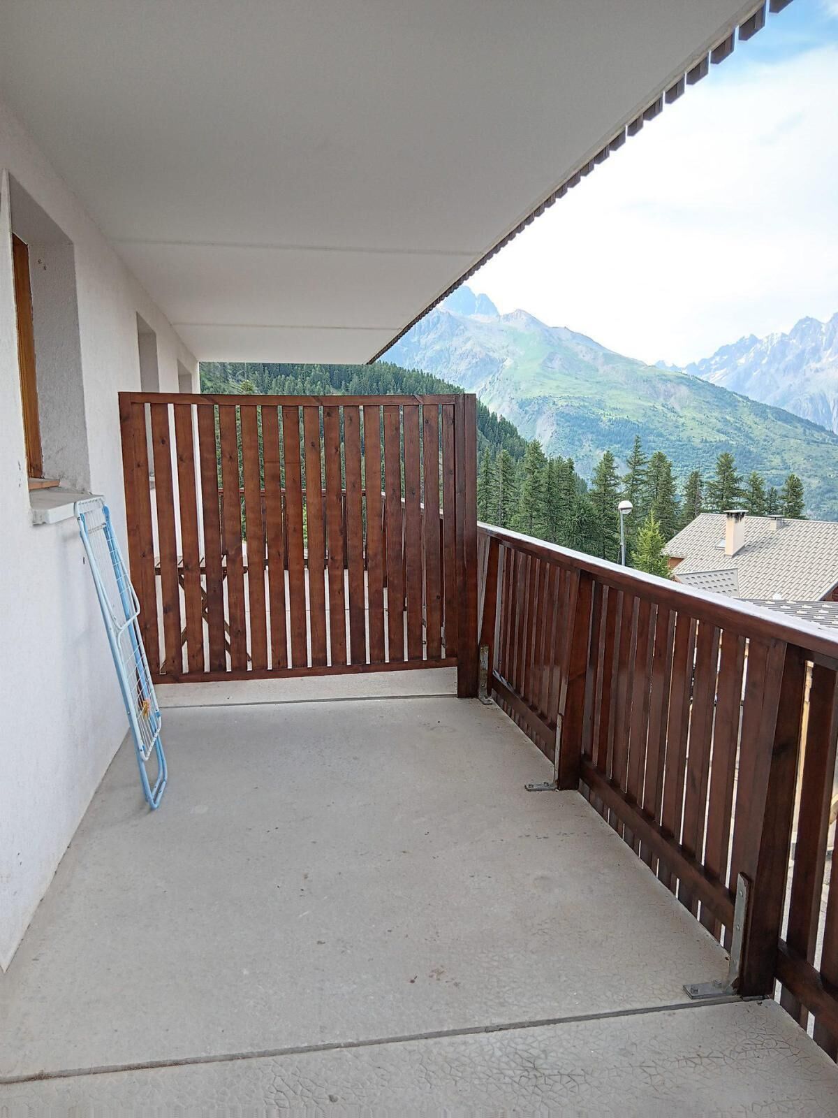 A balcony with a wooden fence, a concrete floor, and a view of mountains.