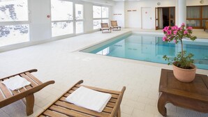 An indoor swimming pool with clear windows, wooden lounge chairs, and a potted plant. - Wifi, 1st floor, view mountain, swimming pool, balcony, parking, tv, ski locker, 35m² (Puy-Saint-Vincent)