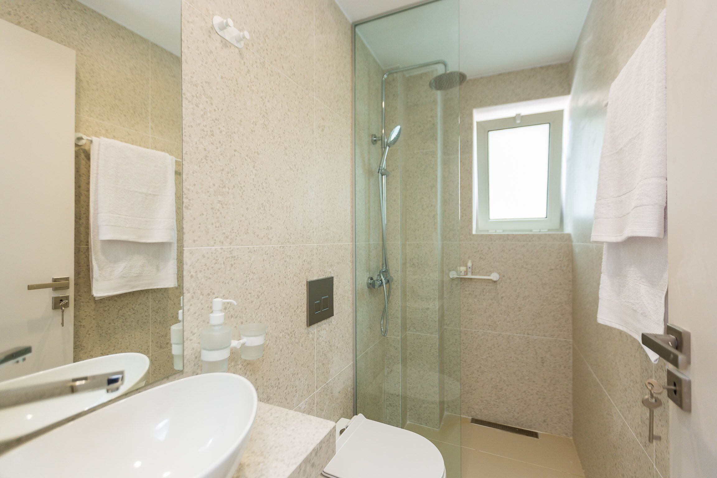 A modern bathroom with a glass-enclosed shower, a sink, and a toilet.