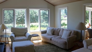 Ein geräumiges Wohnzimmer mit großem Fenster, einem Sofa, einem Sessel und einem Couchtisch.