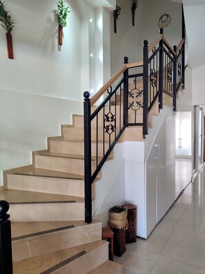 A staircase with a black railing and beige steps, leading to a landing with a white wall and a hanging plant. - Neoss Boutique Hotel (Seferihisar)