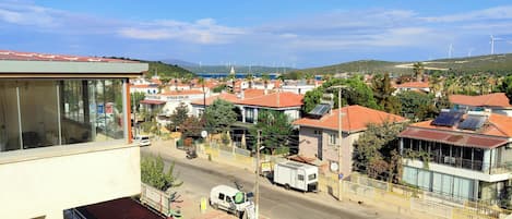 Un barrio residencial con casas, una calle y aerogeneradores a lo lejos.