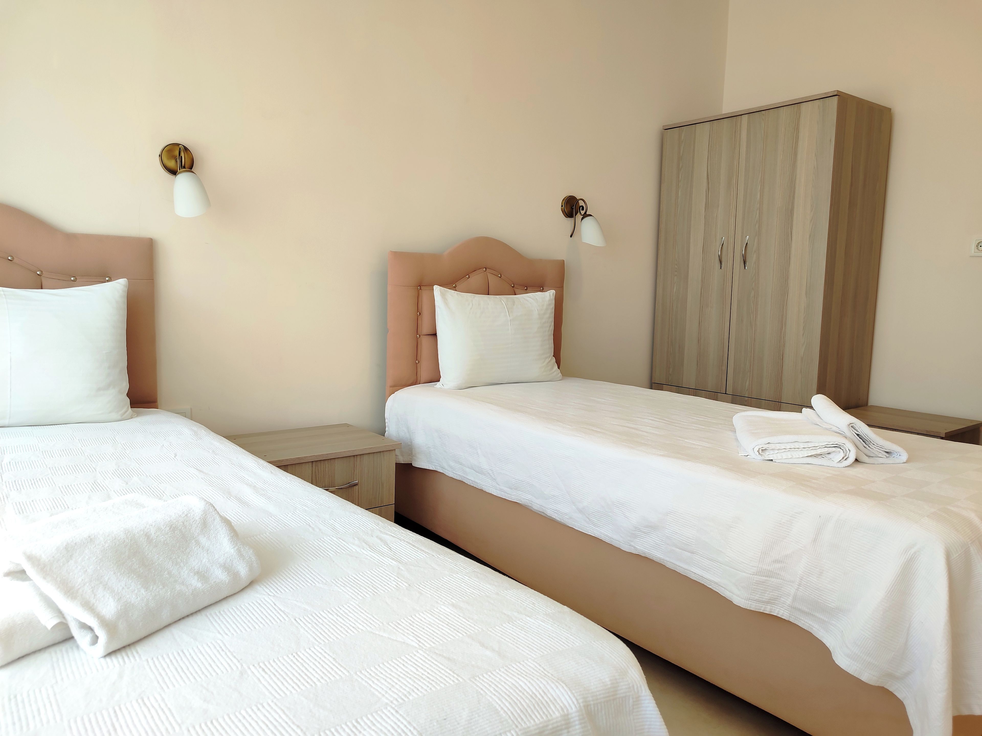 Une chambre d’hôtel avec deux lits, une armoire et des lampes de chevet.