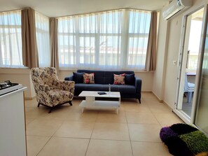 A living room with a sofa, a chair, a coffee table, and a window with curtains. - Neoss Boutique Hotel (Seferihisar)