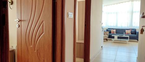 Una puerta de madera con manija, que da a una sala de estar con un sofá y una mesa de centro.