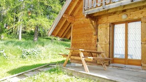 Een houten blokhut met een picknicktafel buiten, omringd door groen.