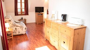 A cozy room with a sofa, wooden cabinet, television, and a window with curtains. - Wifi, 1st floor, swimming pool, balcony, tv, 45m², Saint Lary Soulan (Vignec)