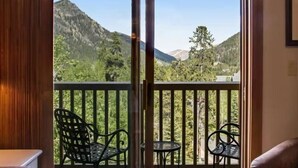 Ein Zimmer mit einer Schiebetür und einem Balkon, der zwei Stühle und einen kleinen Tisch bietet.
