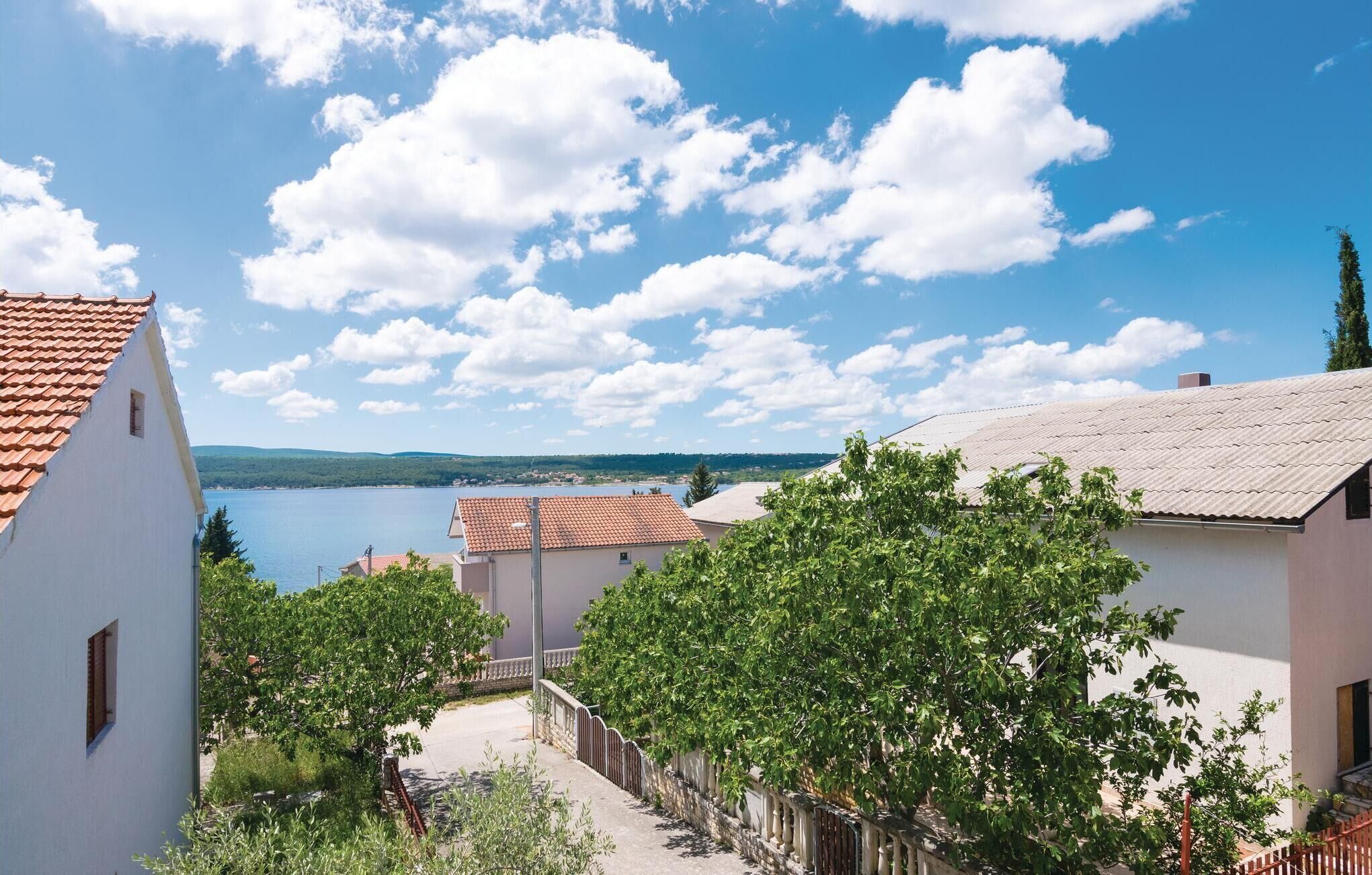Un pueblo costero con edificios blancos, cielo despejado y un lago al fondo.