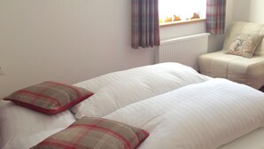 A bedroom with two beds, plaid pillows, a radiator, and a chair with a cushion. - Kitz Residenz 6, Kaprun, Zell am See, Salzburg (Kaprun)