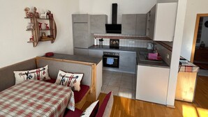 A compact living space with a kitchenette, a sofa with plaid bedding, and a small dining table. - Kitz Residenz 6, Kaprun, Zell am See, Salzburg (Kaprun)