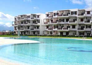 Ett hotell med flera våningar, balkonger och en swimmingpool.