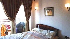 A hotel room with a bed, curtains, a wall-mounted light, and a framed picture. - Studio in Mirador Golf 4119 (Cabo Negro)