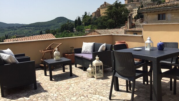 Une terrasse sur le toit, aménagée avec des meubles en osier, une table et des lanternes.