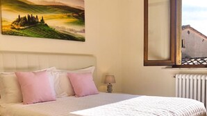 Une chambre avec un grand lit, un tableau représentant un paysage, une fenêtre donnant sur un beau panorama et un radiateur.