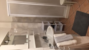 Une salle de bain avec une baignoire, des toilettes et un lavabo. Il y a des serviettes et un panier sur le sol.