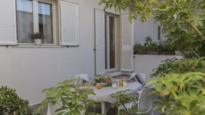 A small patio with a table set for two, surrounded by potted plants and a white fence. - Brezza Marina by Interhome (Scicli)
