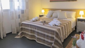 A hotel room with a bed, two bedside lamps, a painting on the wall, and a window with curtains. - Brezza Marina by Interhome (Scicli)