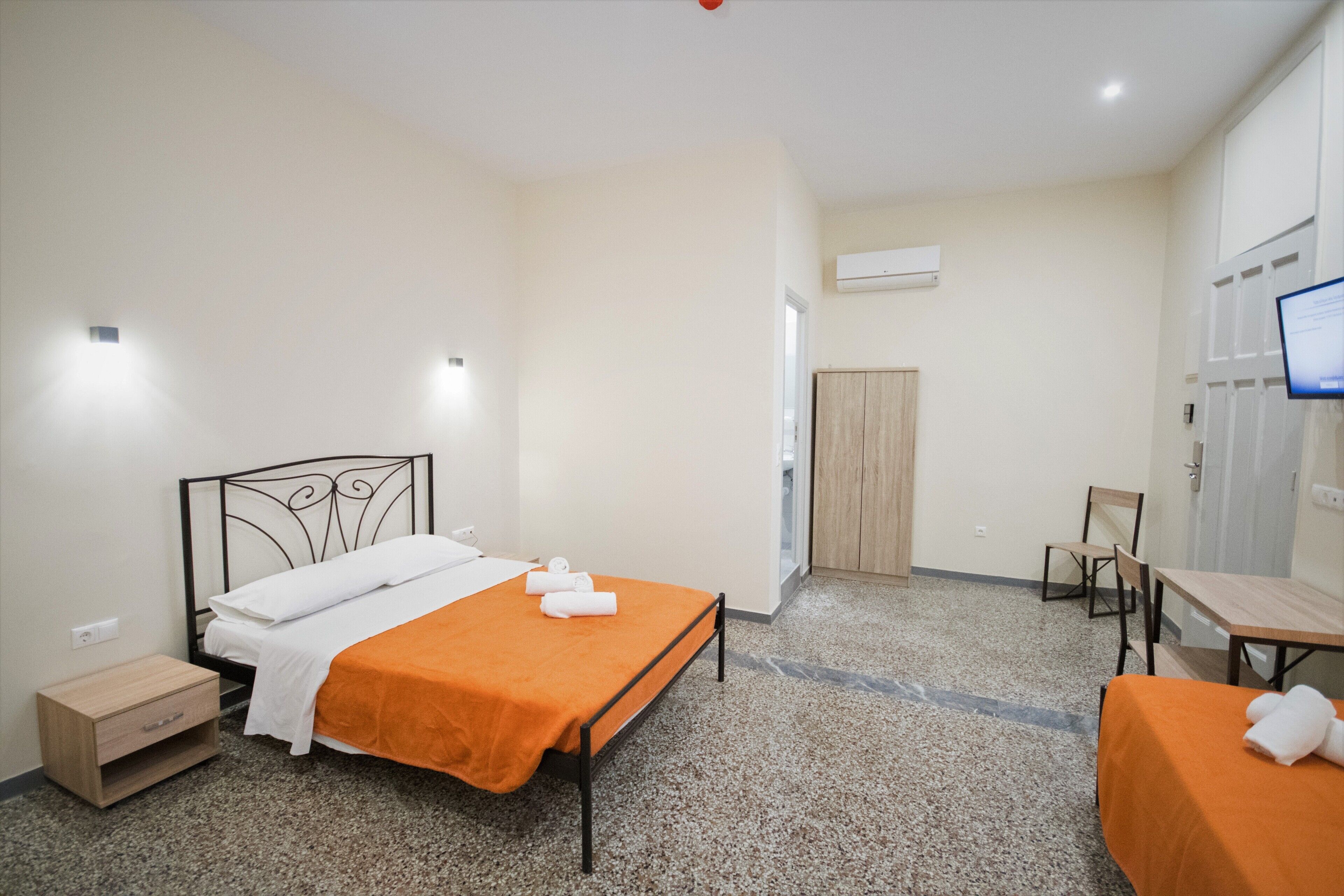 Ein Hotelzimmer mit einem Bett, einem Schreibtisch, einem Sessel, einem Kleiderschrank und einer Klimaanlage.