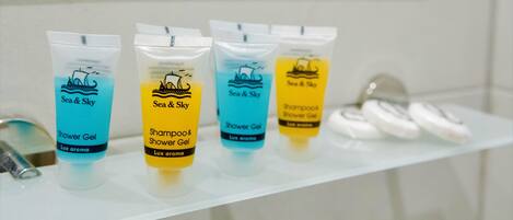 Four toiletry bottles on a bathroom shelf.