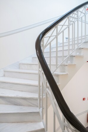 A staircase with white marble steps and a black handrail. - Athens Psiri Hotel (Athens)