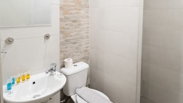Een badkamer met een witte wastafel, toilet en douche.