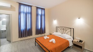 A hotel room with a bed, a nightstand, a wall-mounted light, and a bathroom visible through an open door. - Athens Psiri Hotel (Athens)