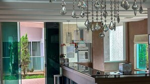 A hotel lobby with a chandelier, a reception desk, and a view of the outdoors. - Oasis Hotel (Araguaina)