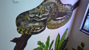 A large, realistic painting of a snake on a wooden branch.