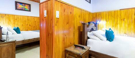 A room with two wooden beds, a wooden wardrobe, and a small table.