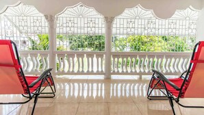 A room with two red chairs and a white balcony railing with decorative patterns. - Runaway Bay Gem Villa (Runaway Bay)