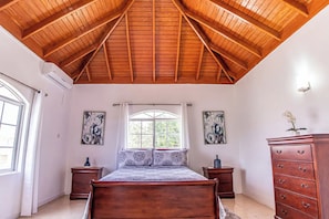 A bedroom with a wooden ceiling, a bed, two nightstands, a dresser, and two framed pictures on the walls. - Runaway Bay Gem Villa (Runaway Bay)