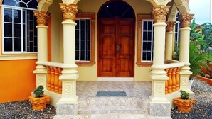 A building entrance with a wooden door, columns, and steps leading up to it. - I Heart JA Me Lo Dio Dios Ocho Rios (Ocho Rios)