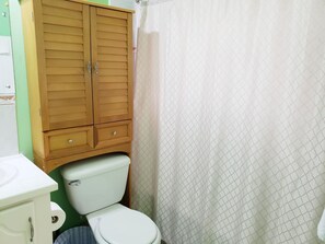 A bathroom with a wooden wardrobe, a toilet, and a patterned shower curtain. - I Heart JA Willow Garden Retreat-Mona (Kingston)