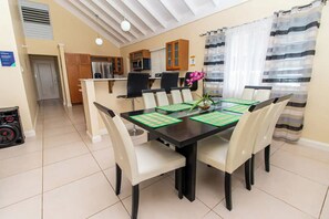 Uma sala de jantar com uma mesa preta, cadeiras brancas e um vaso de flores.